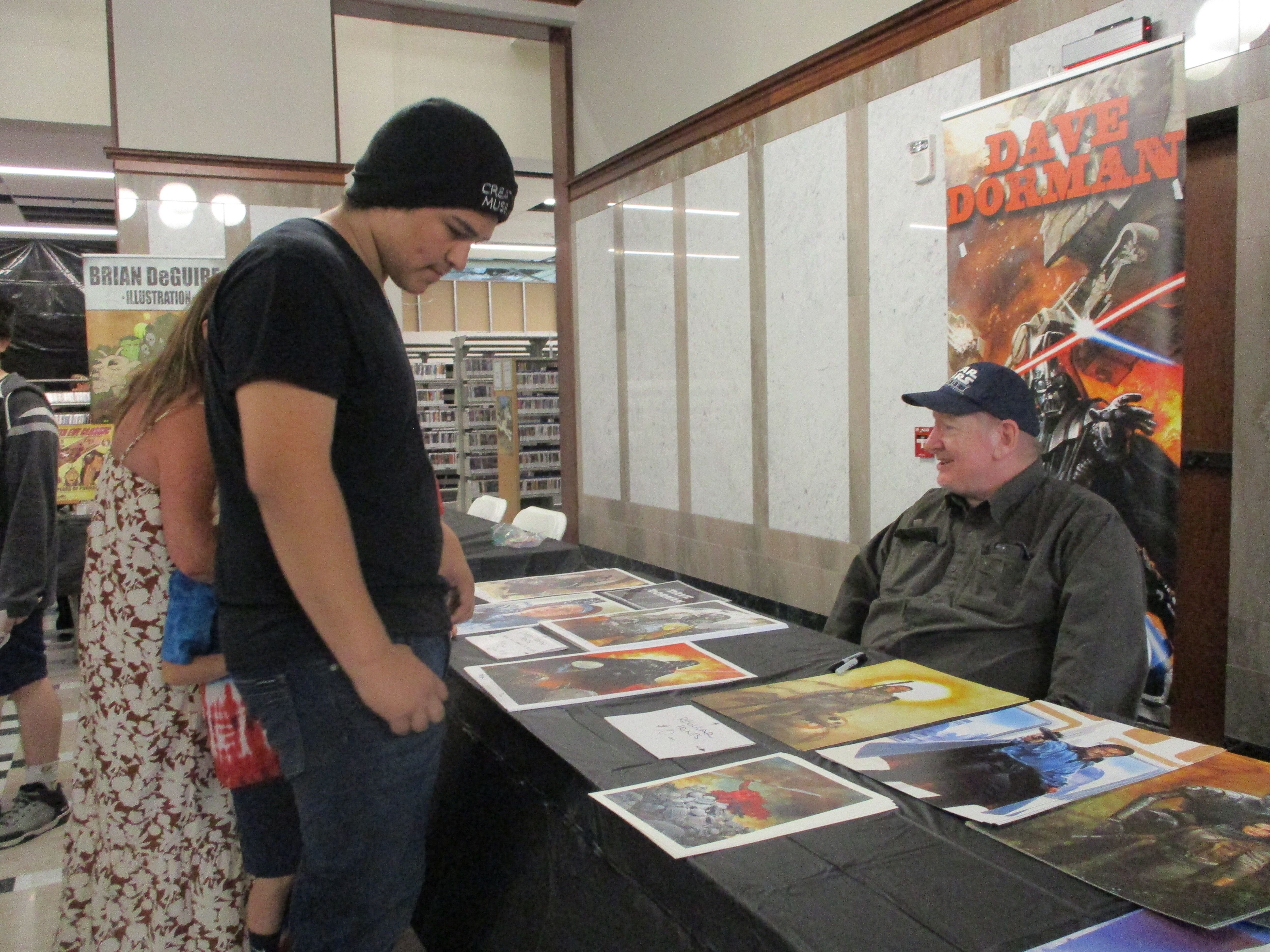 Daniel Ruiz of Joliet looks at Lucasfilm prints put on display for sale by Dave Dorman at Star Wars Day in Joliet on Saturday, June 4 2022.